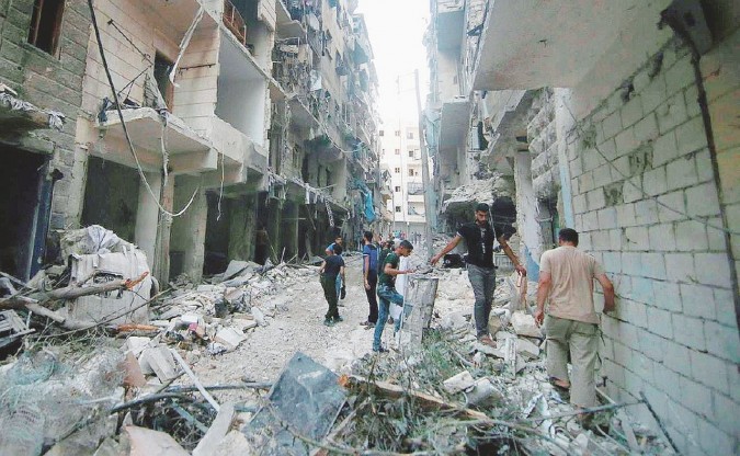 Abitanti di Aleppo fra le macerie di un quartiere dopo l’ennesimo raid aereo -  Ansa