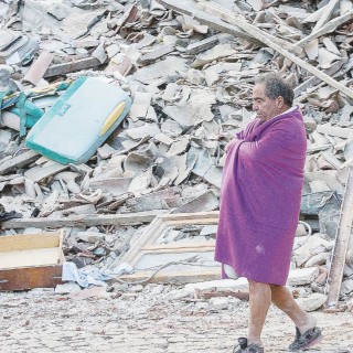 Dopo la notte - Un uomo cammina davanti alle rovine di quel che resta di Amatrice dopo la scossa - Ansa