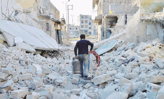 La fatica di sopravvivere - Un uomo torna a casa con le scorte attraverso una delle strade in macerie di Aleppo - Ansa