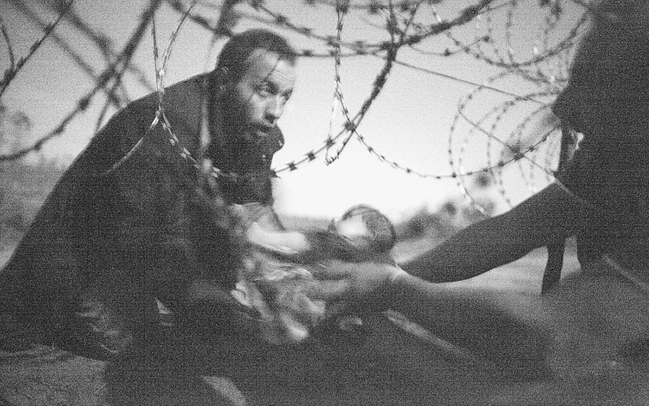 Filo spinato - Un uomo porge il suo bambino a un altro migrante al di là del filo spinato lungo la frontiera serbo-ungherese a Röskze. È la foto vincitrice dell’ australiano Warren Richardson - LaPresse Lontanissimi eppure tra noi. I volti vittoriosi dei profughi