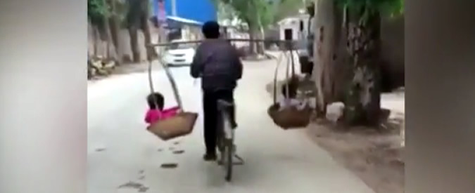 Copertina di Cina, papà equilibrista: trasporta i bambini in bici all’interno di due ceste