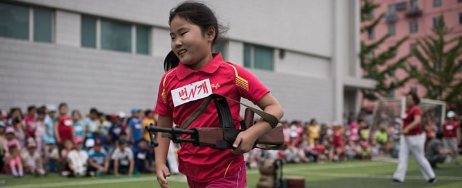 Copertina di Corea del Nord, i macabri giochi della gioventù: i bimbi staccano la testa ai manichini con il mini fucile d’assalto