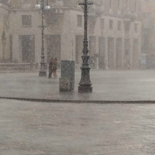 Lecce, il bacio dei fidanzati sotto il diluvio nella piazza deserta. Il fotografo: “Non li conosco, ma li trovo bellissimi”