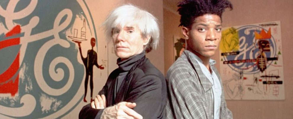 Davanti la sua opera - Jean-Michel Basquiat e il suo mentore, Andy Warhol. Basquiat con una delle sue celebri opere pittoriche Basquiat, inno alla gioia della (totale) ribellione