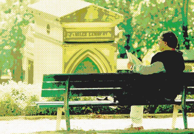 Solitudine tombale - Un turista legge i giornali seduto su una panchina del cimitero parigino di Père-Lachaise - Ansa La pazienza di Gasparino e il frastuono della città