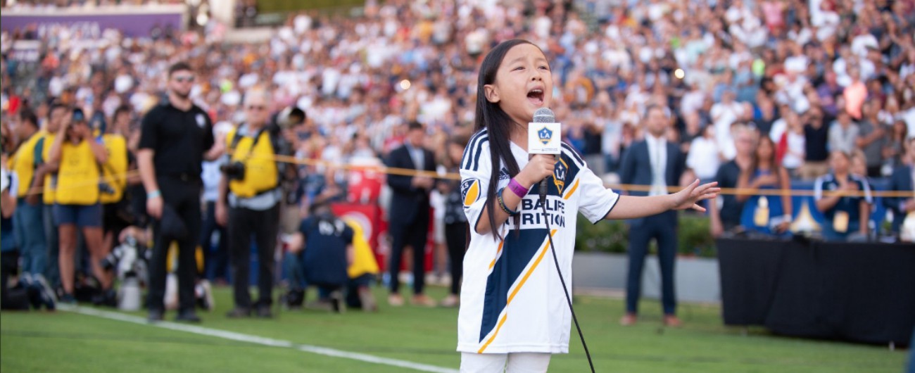 Copertina di Che voce, che grinta, che personalità. La piccola incanta lo stadio con una performance da star