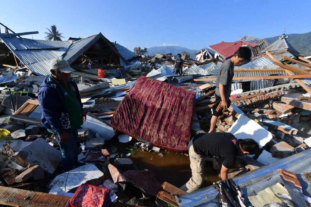 Indonesian men search for a family member at their damaged house in the Balaroa village in Palu, Indonesia’s Central Sulawesi on October 1, 2018. – The death toll nearly doubled to 832 but was expected to rise further after a disaster that has left the island of Sulawesi reeling. (Photo by ADEK BERRY / AFP)