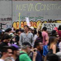 People protest in front of a wall reading "New Constitution" in Santiago, on October 25, 2019, a week after violence protests started. – Demonstrations against a hike in metro ticket prices in Chile’s capital exploded into violence on October 18, unleashing widening protests over living costs and social inequality. (Photo by Martin BERNETTI / AFP)