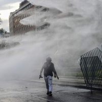 A demonstrator is sprayed water by the police in Santiago, on October 25, 2019, a week after violence protests started. – Demonstrations against a hike in metro ticket prices in Chile’s capital exploded into violence on October 18, unleashing widening protests over living costs and social inequality. (Photo by Martin BERNETTI / AFP)