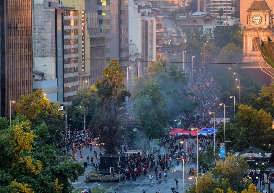 A man demonstrates in front of police in Santiago, on October 25, 2019, a week after violence protests started. – Demonstrations against a hike in metro ticket prices in Chile’s capital exploded into violence on October 18, unleashing widening protests over living costs and social inequality. (Photo by MARTIN BERNETTI / AFP)