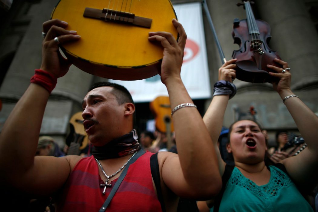 Demonstrators hold up their instruments after performing Chilean musician Victor Jara’s "The right to live in peace" in Santiago, on October 25, 2019, a week after violence protests started. – Demonstrations against a hike in metro ticket prices in Chile’s capital exploded into violence on October 18, unleashing widening protests over living costs and social inequality. (Photo by Pablo VERA / AFP)