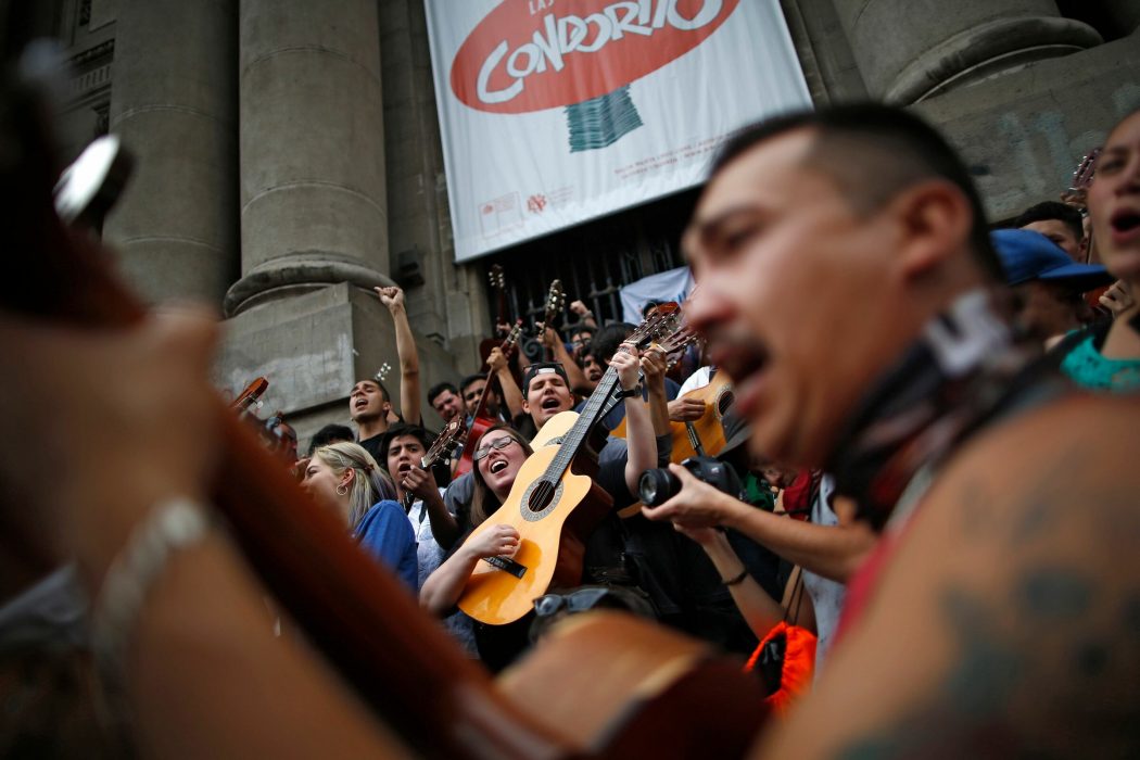Demonstrators play the guitar performing Chilean musician Victor Jara’s "The right to live in peace" in Santiago, on October 25, 2019, a week after violence protests started. – Demonstrations against a hike in metro ticket prices in Chile’s capital exploded into violence on October 18, unleashing widening protests over living costs and social inequality. (Photo by Pablo VERA / AFP)