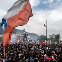 People demonstrate with a Chilean national flag in Santiago, on October 25, 2019, a week after protests started. – Demonstrations against a hike in metro ticket prices in Chile’s capital exploded into violence on October 18, unleashing widening protests over living costs and social inequality. (Photo by Pedro Ugarte / AFP)