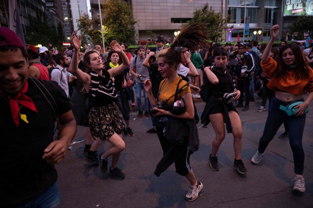 Demonstrators dance in Santiago, on October 25, 2019, a week after protests started. – Demonstrations against a hike in metro ticket prices in Chile’s capital exploded into violence on October 18, unleashing widening protests over living costs and social inequality. (Photo by Pedro Ugarte / AFP)