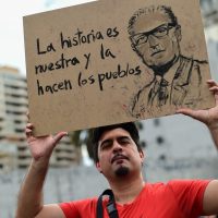 A man holds a sign depicting Chilean late President (1970-73) Salvador Allende reading "History is ours and people make it" in Santiago, on October 25, 2019, a week after violence protests started. – Demonstrations against a hike in metro ticket prices in Chile’s capital exploded into violence on October 18, unleashing widening protests over living costs and social inequality. (Photo by Martin BERNETTI / AFP)