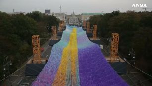 Copertina di Muro di Berlino, 2mila metri di rete da pesca di fronte alla Porta di Brandeburgo. La suggestiva installazione per l’anniversario della caduta