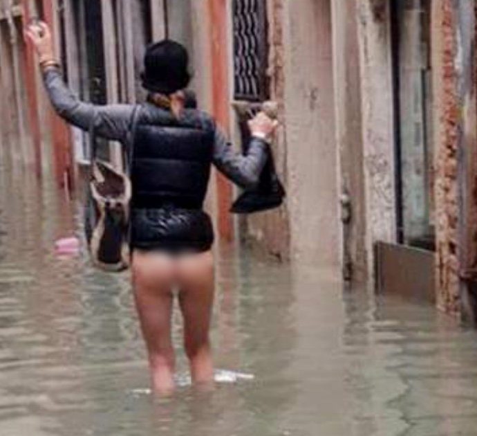Acqua alta a Venezia, una donna cammina senza vestiti per la calle allagata: la foto diventa un simbolo. “Siamo rimasti così, in mutande”