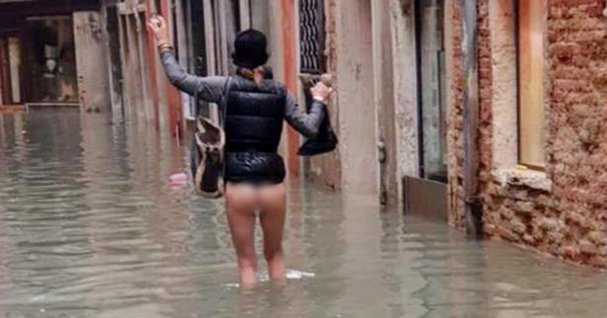 Acqua alta a Venezia, una donna cammina senza vestiti per la calle allagata: la foto diventa un simbolo. “Siamo rimasti così, in mutande”