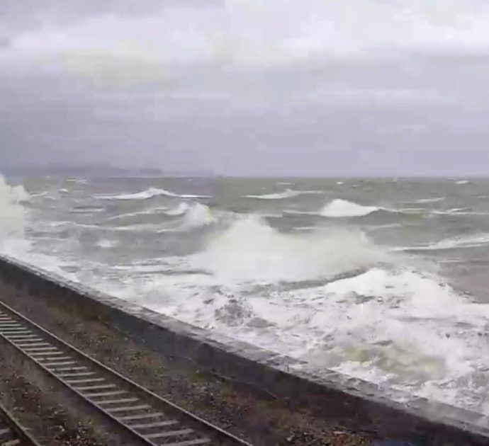 Paura a bordo, il treno passa accanto al mare in tempesta: la forza delle onde distrugge i finestrini