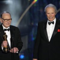 FILE – In this Feb. 25, 2007 file photo, Italian composer Ennio Morricone, left, accepts an honorary Oscar for his contributions to the art of film music as director Clint Eastwood looks on during the 79th Academy Awards telecast in Los Angeles. Morricone, who created the coyote-howl theme for the iconic Spaghetti Western “The Good, the Bad and the Ugly” and the soundtracks such classic Hollywood gangster movies as “The Untouchables,” died Monday, July 6, 2020 in a Rome hospital at the age of 91. (AP Photo/Mark J. Terrill, file)