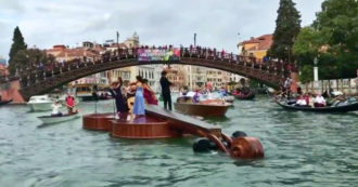 Copertina di Venezia, i musicisti suonano a bordo di un violino gigante sul Canal Grande – Video