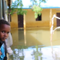 A boy looks out at the flooded street.