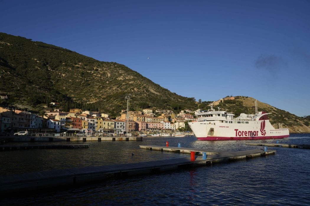 A ferry boat enters the port of the tiny Tuscan island of Isola del Giglio, Italy, Thursday, Jan. 13, 2022. Italy on Thursday is marking the 10th anniversary of the Costa Concordia cruise ship disaster with a daylong commemoration, honoring the 32 people who died but also the extraordinary response by the residents of Giglio who took in the 4,200 passengers and crew from the ship on that rainy Friday night and then lived with the Concordia carcass for another two years before it was hauled away for scrap. (AP Photo/Andrew Medichini)