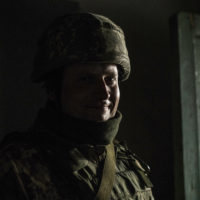 A Ukrainian soldier smiles in a shelter during shelling by pro-Russian separatists in the village of Novoluhanske, Luhansk region, Ukraine, Saturday, Feb. 19, 2022. Separatist leaders in eastern Ukraine have ordered a full military mobilization amid growing fears in the West that Russia is planning to invade the neighboring country. The announcement on Saturday came amid a spike in violence along the line of contact between Ukrainian forces and the pro-Russia rebels in recent days. (AP Photo/Oleksandr Ratushniak)