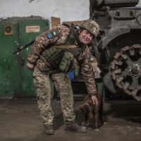 A Ukrainian soldier pets a dog after shelling by pro-Russian separatists in the village of Novoluhanske, Luhansk region, Ukraine, Saturday, Feb. 19, 2022. Separatist leaders in eastern Ukraine have ordered a full military mobilization amid growing fears in the West that Russia is planning to invade the neighboring country. The announcement on Saturday came amid a spike in violence along the line of contact between Ukrainian forces and the pro-Russia rebels in recent days. (AP Photo/Oleksandr Ratushniak)