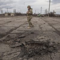 A Ukrainian soldier looks at a hole from a shell fired by pro-Russian separatists in the village of Novoluhanske, Luhansk region, Ukraine, Saturday, Feb. 19, 2022. Separatist leaders in eastern Ukraine have ordered a full military mobilization amid growing fears in the West that Russia is planning to invade the neighboring country. The announcement on Saturday came amid a spike in violence along the line of contact between Ukrainian forces and the pro-Russia rebels in recent days. (AP Photo/Oleksandr Ratushniak)
