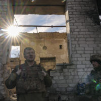 Ukrainian servicemen stand by a destroyed house near the frontline village of Krymske, Luhansk region, in eastern Ukraine, Saturday, Feb. 19, 2022. Ukrainian President Volodymyr Zelenskyy, facing a sharp spike in violence in and around territory held by Russia-backed rebels and increasingly dire warnings that Russia plans to invade, on Saturday called for Russian President Vladimir Putin to meet him and seek resolution to the crisis. (AP Photo/Vadim Ghirda)