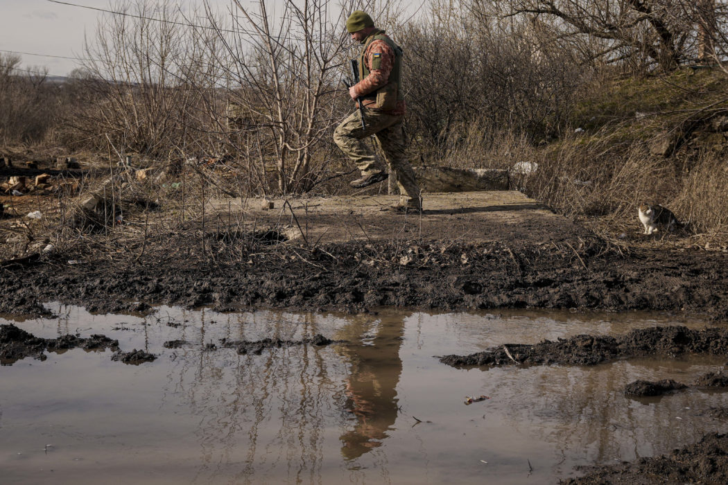 A Ukrainian serviceman jumps to shake the mud from his boots near the frontline village of Krymske, Luhansk region, in eastern Ukraine, Saturday, Feb. 19, 2022. Ukrainian President Volodymyr Zelenskyy, facing a sharp spike in violence in and around territory held by Russia-backed rebels and increasingly dire warnings that Russia plans to invade, on Saturday called for Russian President Vladimir Putin to meet him and seek resolution to the crisis. (AP Photo/Vadim Ghirda)