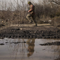 A Ukrainian serviceman jumps to shake the mud from his boots near the frontline village of Krymske, Luhansk region, in eastern Ukraine, Saturday, Feb. 19, 2022. Ukrainian President Volodymyr Zelenskyy, facing a sharp spike in violence in and around territory held by Russia-backed rebels and increasingly dire warnings that Russia plans to invade, on Saturday called for Russian President Vladimir Putin to meet him and seek resolution to the crisis. (AP Photo/Vadim Ghirda)