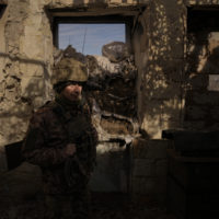 A Ukrainian serviceman walks inside a destroyed house near the frontline village of Krymske, Luhansk region, in eastern Ukraine, Saturday, Feb. 19, 2022. Ukrainian President Volodymyr Zelenskyy, facing a sharp spike in violence in and around territory held by Russia-backed rebels and increasingly dire warnings that Russia plans to invade, on Saturday called for Russian President Vladimir Putin to meet him and seek resolution to the crisis. (AP Photo/Vadim Ghirda)