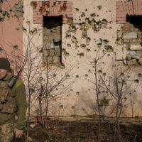 A Ukrainian serviceman walks by a bullet riddled wall of a house near the frontline village of Krymske, Luhansk region, in eastern Ukraine, Saturday, Feb. 19, 2022. Ukrainian President Volodymyr Zelenskyy, facing a sharp spike in violence in and around territory held by Russia-backed rebels and increasingly dire warnings that Russia plans to invade, on Saturday called for Russian President Vladimir Putin to meet him and seek resolution to the crisis. (AP Photo/Vadim Ghirda)