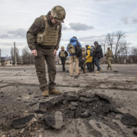A Ukrainian soldier looks at a hole from a shell fired by pro-Russian separatists in the village of Novoluhanske, Luhansk region, Ukraine, Saturday, Feb. 19, 2022. Separatist leaders in eastern Ukraine have ordered a full military mobilization amid growing fears in the West that Russia is planning to invade the neighboring country. The announcement on Saturday came amid a spike in violence along the line of contact between Ukrainian forces and the pro-Russia rebels in recent days. (AP Photo/Oleksandr Ratushniak)