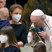 Pope Francis kisses a flag of Ukraine that comes from the city of Bucha as he meets Ukrainian children during the weekly general audience in Paolo VI Hall, Vatican City, 06 April 2022.  ANSA/ETTORE FERRARI