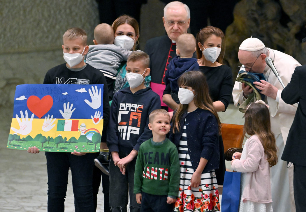Pope Francis (R) kisses a flag of Ukraine that comes from the city of Bucha as he meets Ukrainian children during the weekly general audience in Paolo VI Hall, Vatican City, 06 April 2022.  ANSA/ETTORE FERRARI