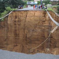 Stranded people stand in front of a bridge that was swept away in Ntuzuma, outside Durban, South Africa, Tuesday, April 12, 2022. Prolonged rains and flooding in South Africa’s KwaZulu-Natal province have claimed dozens of lives, according to local officials. (AP Photo)