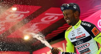 Copertina di Biniam Girmay si ritira dal Giro d’Italia: il ciclista eritreo colpito all’occhio dal tappo dello spumante dopo la prima storica vittoria