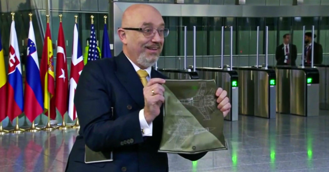 Il ministro della Difesa ucraino mostra ai giornalisti la pochette col disegno di un jet militare: il video dopo la riunione Nato