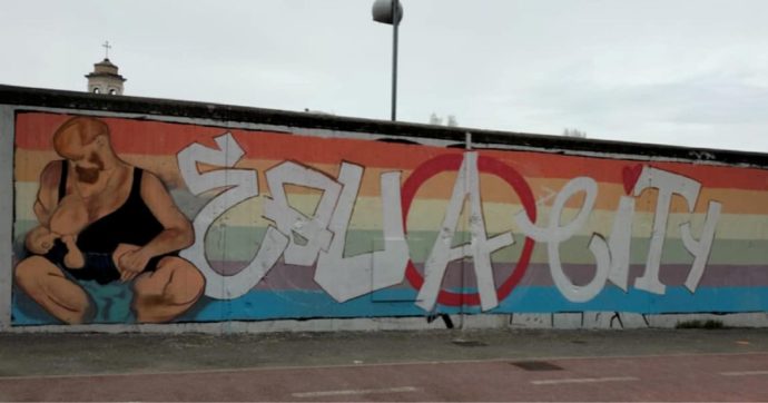 Copertina di Uomo allatta un bimbo: il murale divide Rimini