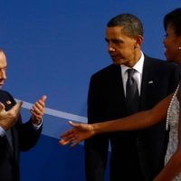 Una delle gaffe storiche: all’arrivo di Obama con la moglie Michelle, l’ex premier si lascia andare a un gesto eloquente di apprezzamento e Obama lo fulmina con lo sguardo