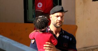 Copertina di Migranti, Lampedusa è al collasso: un carabiniere tiene in braccio una bambina e la tranquillizza aspettando l’arrivo della mamma all’hotspot – Video