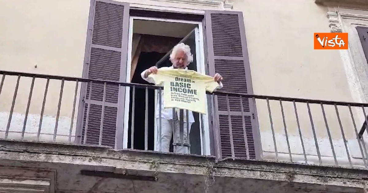 Grillo a Roma mostra una maglia gialla sul reddito universale dal balcone della sede M5s