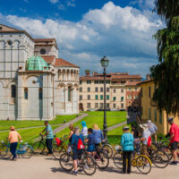 Lucca, Italy – May 5, 2018: Cycloturism in Lucca. Tourists visit the city beautiful medieval historic center in Tuscany