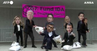 Copertina di Manifestanti con maschere dei leader de G7 a Washington: la protesta per chiedere fondi per l’Associazione per lo Sviluppo