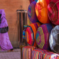 A Muslim woman, wearing a hijab, walks past poufs in the market, Marrakech, Morocco.
