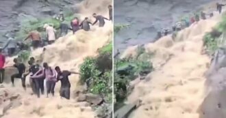 Copertina di Piogge torrenziali travolgono i turisti in visita ad una cascata: loro formano una catena umana per resistere alla forza dell’acqua – VIDEO