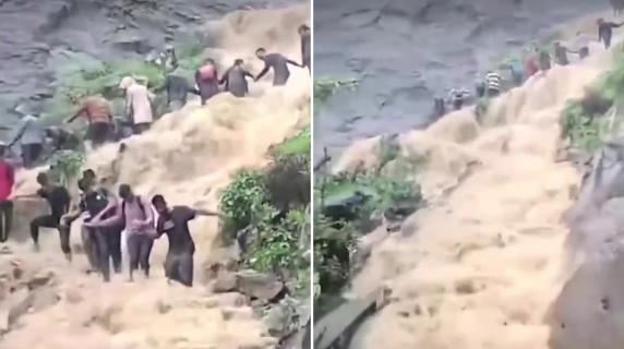 Piogge torrenziali travolgono i turisti in visita ad una cascata: loro formano una catena umana per resistere alla forza dell’acqua – VIDEO